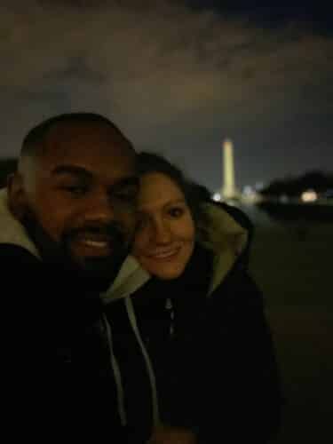 couple poses at night in front of Washington Monument