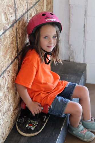 a small child sits on an upside down skateboard and smiles