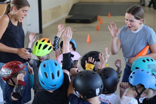 two female Carry On teachers high five a group of kids with helmets on