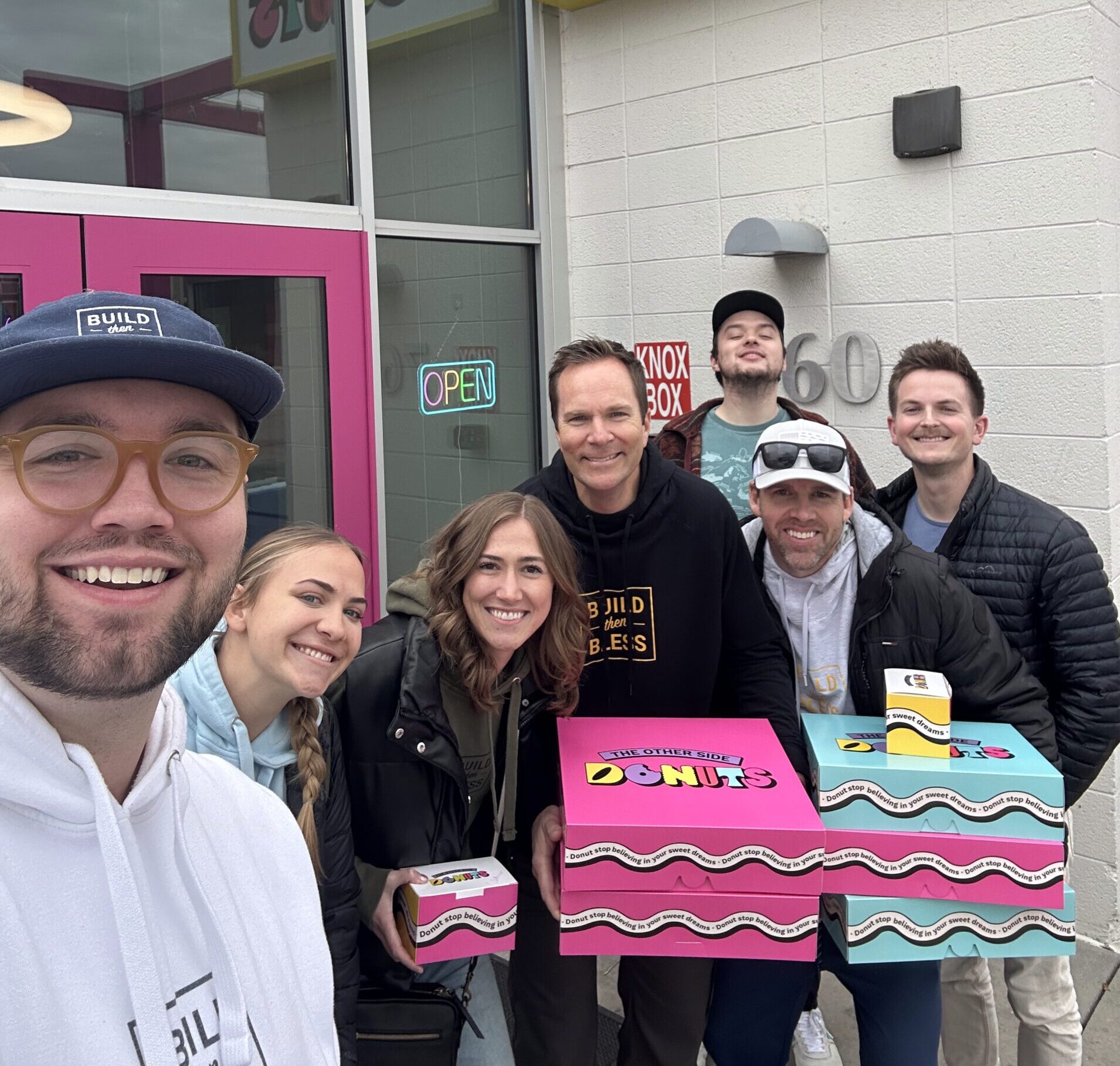 co-workers pose with donut boxes